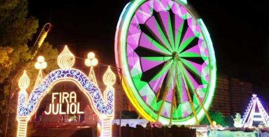 Foto de la feria de Julio en Valencia, se ve la entrada a la feria de noche y la noria iluminada con luces
